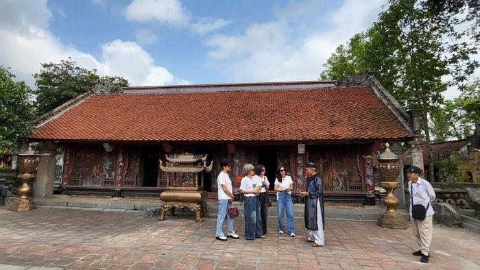 Ông Phạm Văn Quyển, Phó Ban Khánh tiết đền Thánh Nguyễn (áo đen) đang giới thiệu với du khách về lịch sử đền Thánh Nguyễn. Ảnh: Phan Hiếu
