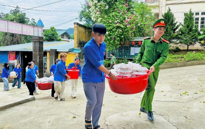 Lực lượng Tiếp sức mùa thi tiếp nhận đồ ăn trưa cho các thí sinh sau khi hoàn thành bài thi tại điểm trường THCS và THPT Thượng Lâm. Ảnh: Như Quỳnh