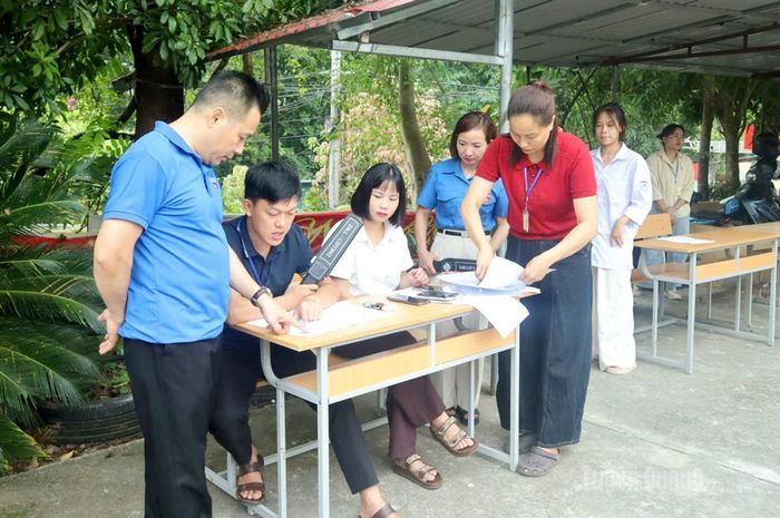 Cán bộ làm nhiệm vụ tại điểm thi Trường THPT Yên Minh, xã Yên Minh rà soát danh sách để kịp thời hỗ trợ thí sinh chưa đến phòng thi. Ảnh: Phạm Hoan