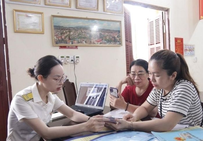 Công chức Thuế cơ sở 5 tỉnh Lạng Sơn hướng dẫn người nộp thuế thực hiện nộp thuế trên ứng dụng eTax Mobile. Ảnh: CTV.
