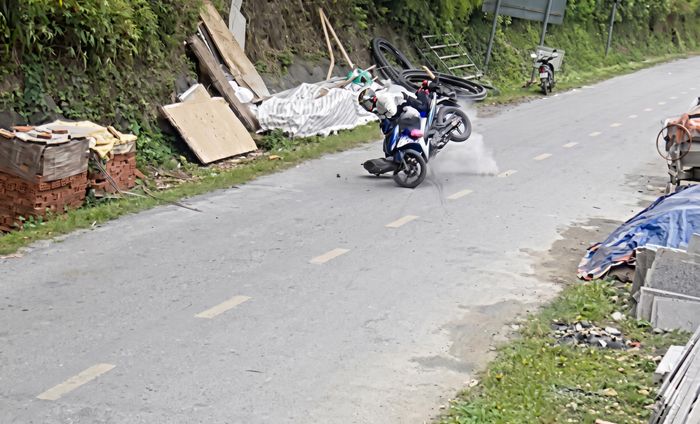 Đá lở bất ngờ từ vách núi, hất văng người đi xe máy xuống đường. (Ảnh cắt từ clip).