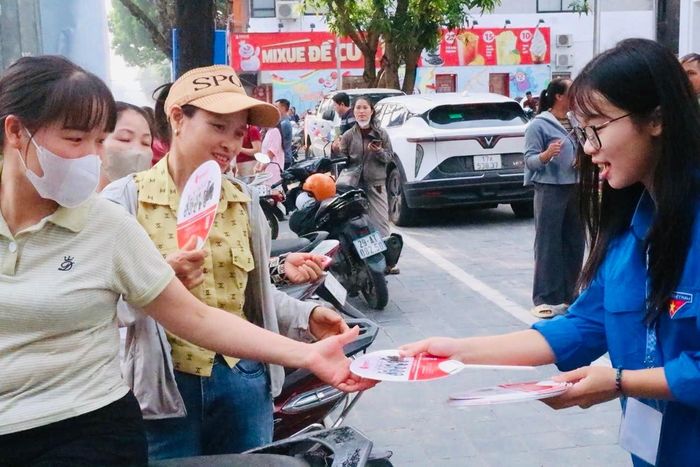 Thanh niên tình nguyện tặng quạt cho người nhà thí sinh tại một điểm thi trên địa bàn xã Sóc Sơn. Ảnh: Tùng Nguyễn.