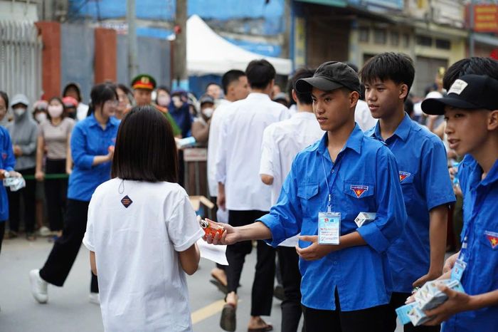 Thanh niên tình nguyện xã Hát Môn phát nước, sữa cho các thí sinh. Ảnh: HM