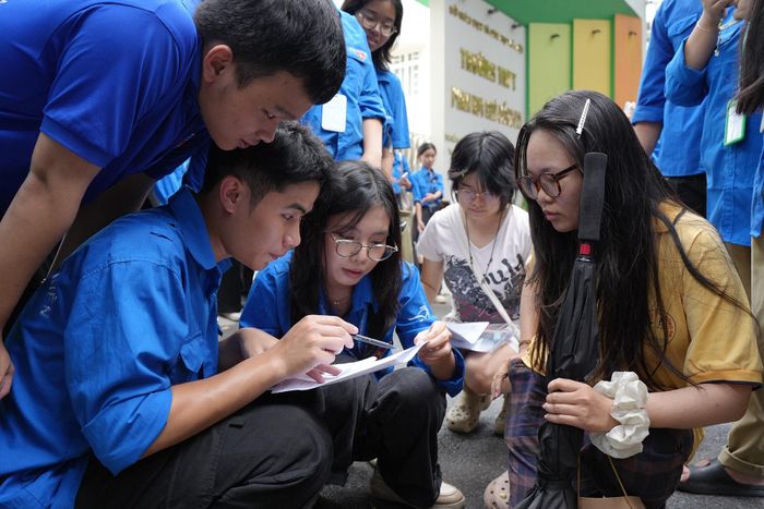 Tình nguyện viên hỗ trợ giải đề ngay ngoài điểm thi để thí sinh có thêm sự an tâm. Ảnh: Phạm Mạnh