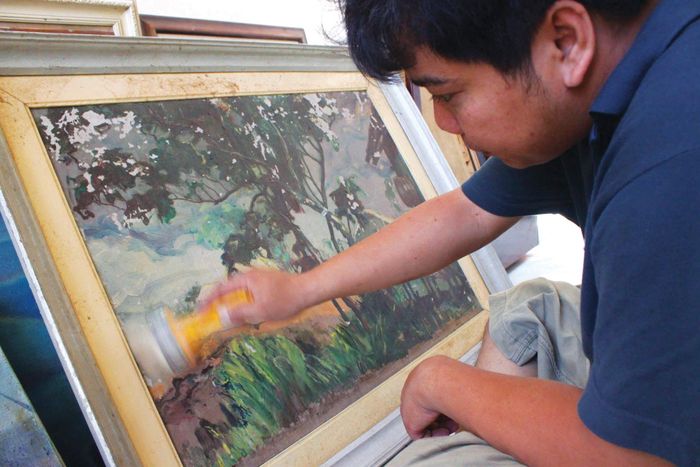 Họa sĩ Võ Bình đang phục chế tranh