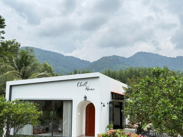 Nhà được sơn màu trắng nổi bật, nằm ở dưới chân núi. Xung quanh là vườn trái cây nên không khí mát mẻ, dễ chịu