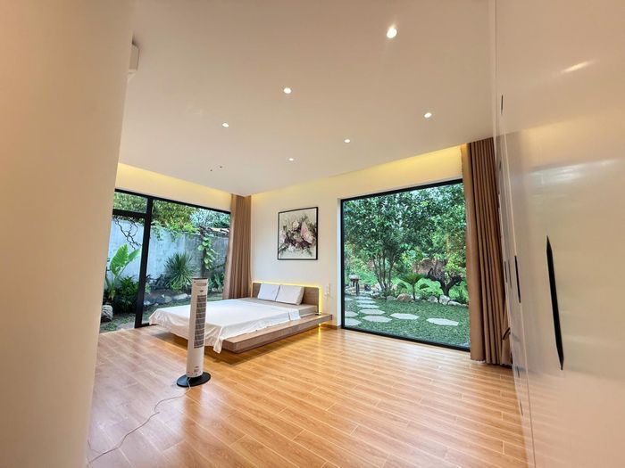 Phòng ngủ của vợ chồng chị Thảo rộng 27m2, có 2 tấm kính lớn với tầm nhìn rộng. Một bên hướng ra bãi cỏ và vườn rau, một bên nhìn ra khu vườn nhiệt đới