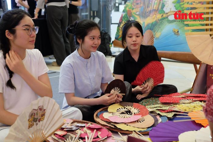 Các bạn trẻ hào hứng nghe những chia sẻ từ nghệ nhân làng nghề làm quạt Chàng Sơn.