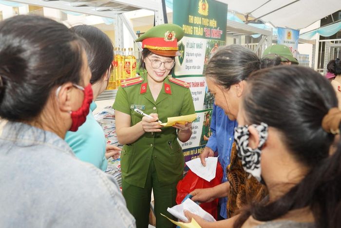 Cán bộ Ban Phụ nữ Công an tỉnh Quảng Ninh tươi cười hỗ trợ người dân nhận quà ở "Gian hàng 0 đồng"