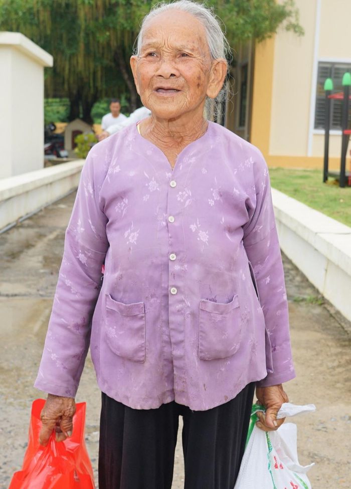 Bà Đặng Thị Ún, 90 tuổi, ở thôn 4, dù tuổi cao nhưng vẫn tự tay xách những phần quà vừa nhận được.