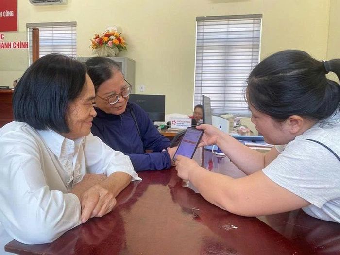 Bà Trương Thị Quang và Nguyễn Thị Thu vui vẻ khi được hướng dẫn đăng ký nhận lương hưu không dùng tiền mặt.