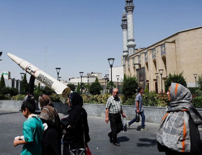 Người dân đi bộ cạnh mô hình tên lửa đặt trên một con phố ở Tehran, Iran. Ảnh: The Guardian