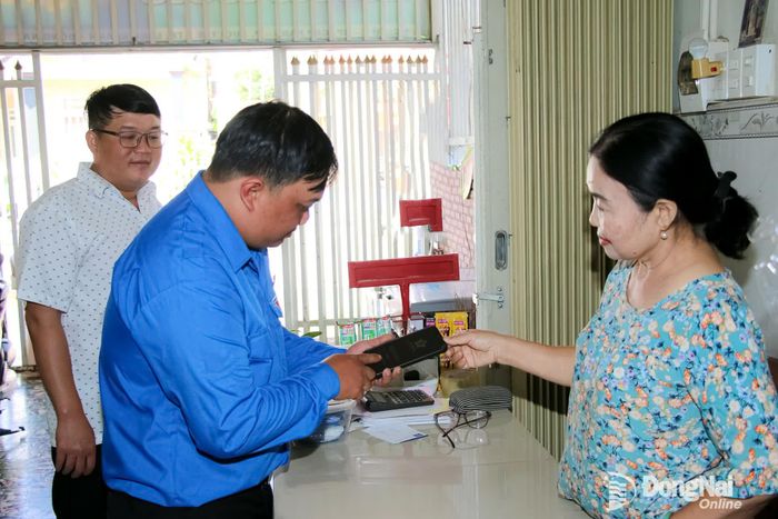 Thành viên Tổ Công nghệ số cộng đồng của khu phố Cấp Rang (phường Bình Lộc) tuyên truyền, hỗ trợ hộ kinh doanh trên địa bàn cài đặt, sử dụng các ứng dụng thanh toán số. Ảnh: Hải Quân