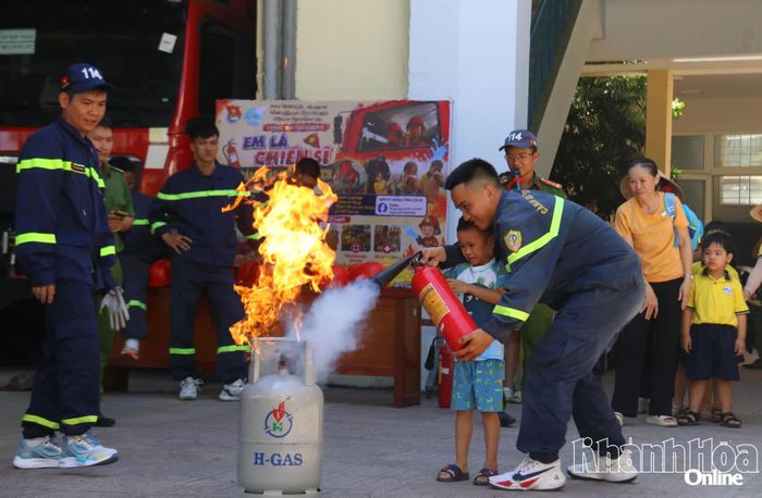 Với sự hỗ trợ của chiến sĩ cảnh sát chữa cháy, chiến sĩ nhí đã có thể dập lửa bằng bình chữa cháy xách tay.