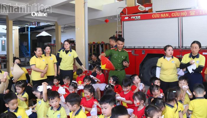 Dưới cái nắng gắt của ngày hè, một cán bộ sử dụng nón lá quạt mát cho các em nhỏ tham gia chương trình.