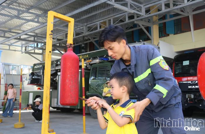 Một em nhỏ thực hành đánh kẻng báo cháy.