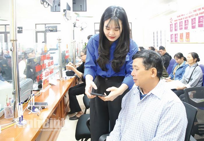 Đoàn viên thanh niên phường Tây Hoa Lư hướng dẫn người dân sử dụng dịch vụ công trực tuyến.Ảnh: Nguyễn Hương