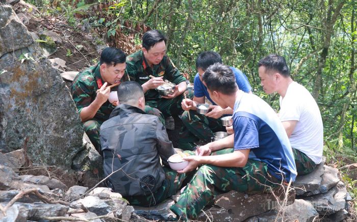 Bữa cơm giản dị bên sườn núi tiếp thêm sức lực cho cán bộ, chiến sĩ sau nhiều giờ bám địa bàn tìm kiếm.
