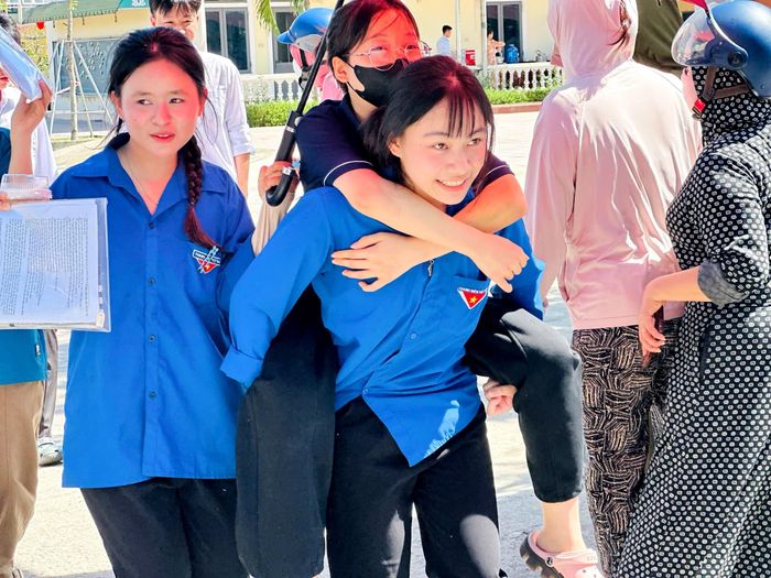 Một thí sinh bị thương ở chân được các bạn tình nguyện viên cõng vào điểm thi