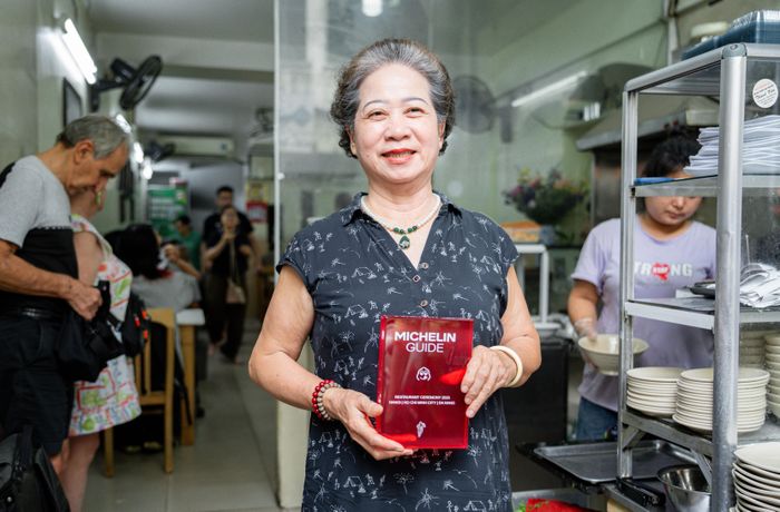  Bà Vân cầm trên tay chứng nhận Bib Gourmand của Michelin Guide 2026 dành cho quán bánh cuốn của mình. 