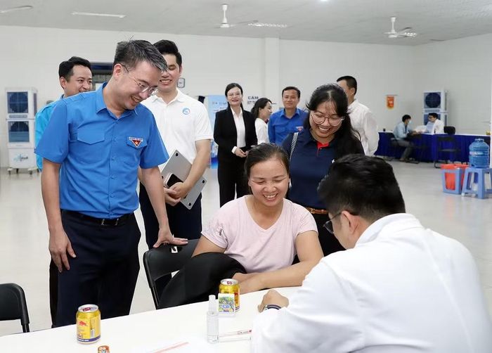 Đại diện Ban tổ chức Ngày hội thăm, trao quà tặng thanh niên công nhân ở khu vực khám bệnh miễn phí.