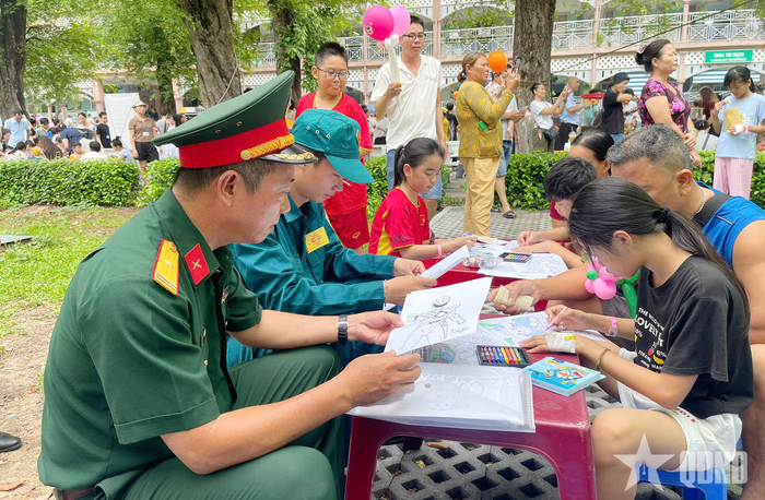 Cán bộ, chiến sĩ Ban CHQS phường Xuân Hòa cùng các em thiếu nhi tô tranh. 