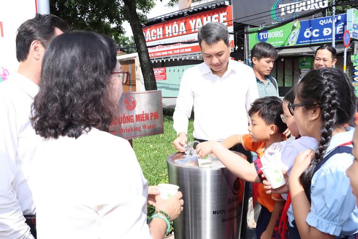  Lãnh đạo phường Tăng Nhơn Phú và các em học sinh trải nghiệm uống nước tại trụ nước uống miễn phí. Ảnh: THU HƯỜNG 