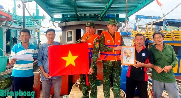 Cán bộ, chiến sĩ Đồn Biên phòng cửa khẩu quốc tế Hà Tiên, Bộ đội Biên phòng tỉnh An Giang tặng cờ Tổ quốc, ảnh Bác Hồ, kết hợp tuyên truyền pháp luật cho ngư dân. Ảnh: Minh Nhòa