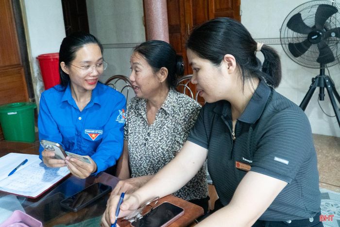 Cán bộ Trung tâm Phục vụ hành chính công xã và thành viên Tổ chuyển đổi số cộng đồng xã Hương Xuân hướng dẫn bà Phan Thị Tường thực hiện dịch vụ công trực tuyến.