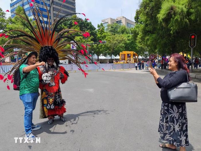 Người dân và du khách lưu giữ những khoảnh khắc đáng nhớ tại lễ diễu hành văn hóa ở Mexico City. (Ảnh: Phương Lan/TTXVN)