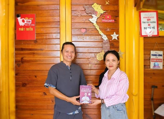 Nhà sáng lập Làng Chữa Lành Trần Hoàng Minh (bên trái) tặng sách cho phóng viên.