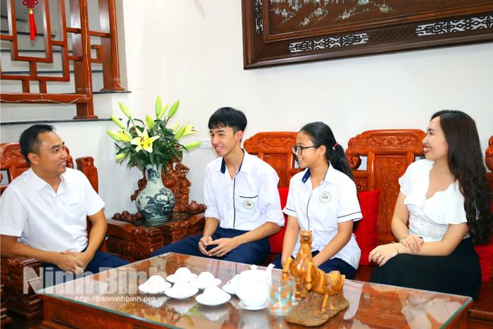 Em Ngô Trung Kiên (thứ 2 từ trái qua phải) chia sẻ thành tích đạt được trong học tập với người thân trong gia đình.