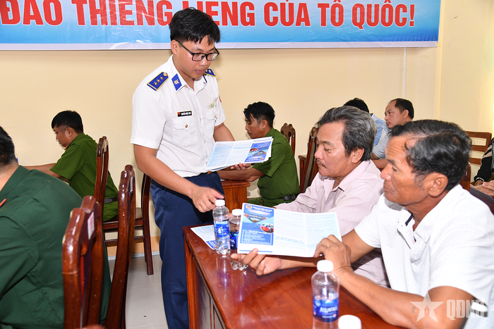 Cán bộ Vùng Cảnh sát biển 4 phát tờ rơi tuyên truyền pháp luật tới ngư dân.