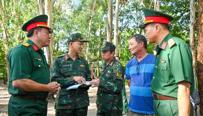  Đại tá Thái Thành Đức, Phó Chủ nhiệm Chính trị Quân khu 7 (bên trái) trao đổi với Đại tá Nguyễn Đình Chuẩn, Phó Chính ủy Bộ Tư lệnh TPHCM (ở giữa) và các đơn vị, nhân chứng về vị trí các rãnh mộ. Ảnh: MẠNH THẮNG 