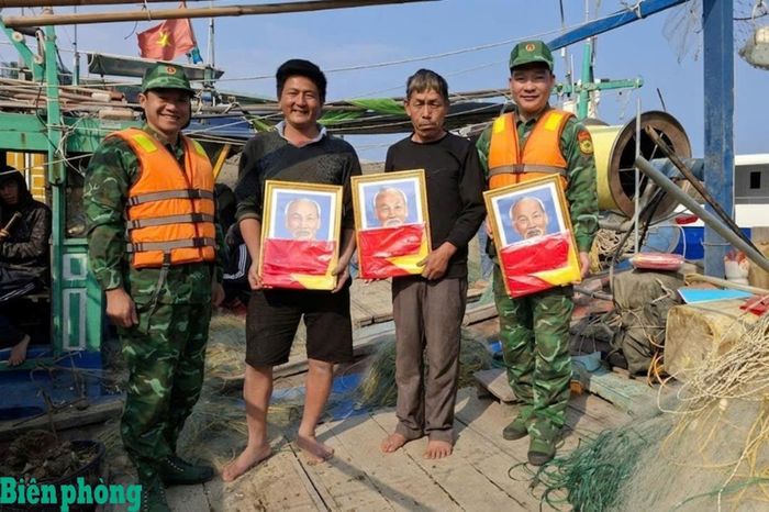 Cán bộ, chiến sĩ Đồn Biên phòng Đảo Trần tặng cờ Tổ quốc và ảnh Bác Hồ cho ngư dân. Ảnh: Nguyễn Thanh Tùng
