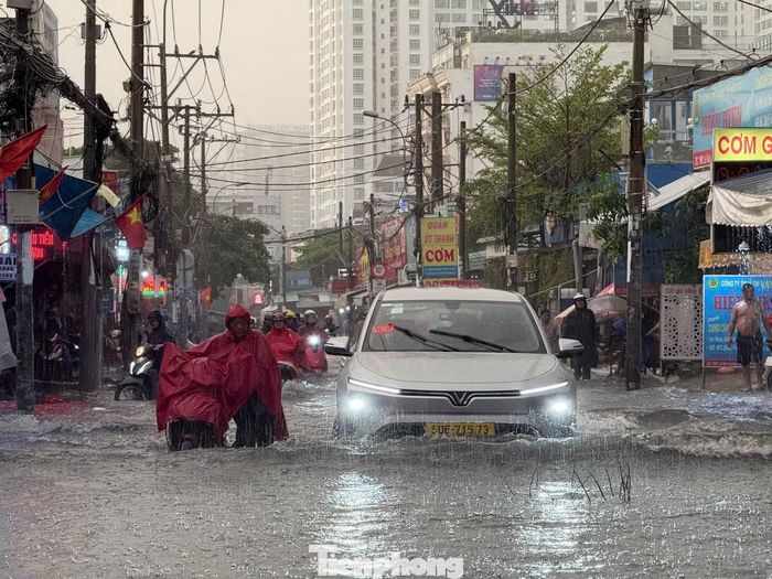 Xe chết máy, chủ phương tiện dắt bộ dưới cơn mưa.