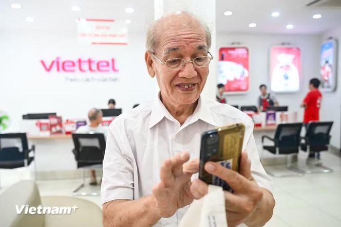 Ông Liên tỏ ra vui mừng khi số điện thoại của mình đã được xác thực nhờ sự hỗ trợ của nhân viên. (Ảnh: Minh Sơn/Vietnam+)