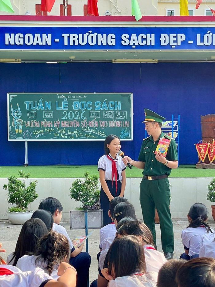 Thiếu tá Vũ Lý Huỳnh trong tiết học biên giới, hướng dân các em học sinh Trường tiểu học Sông Cầu tìm hiểu kiến thức qua trang sách.