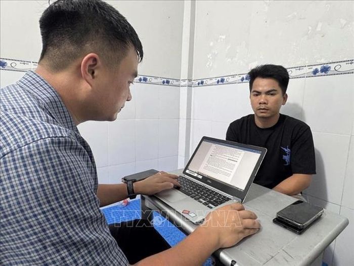 Lấy lời khai của đối tượng Nguyễn Chí Thanh (phải) tại cơ quan công an. Ảnh: TTXVN phát