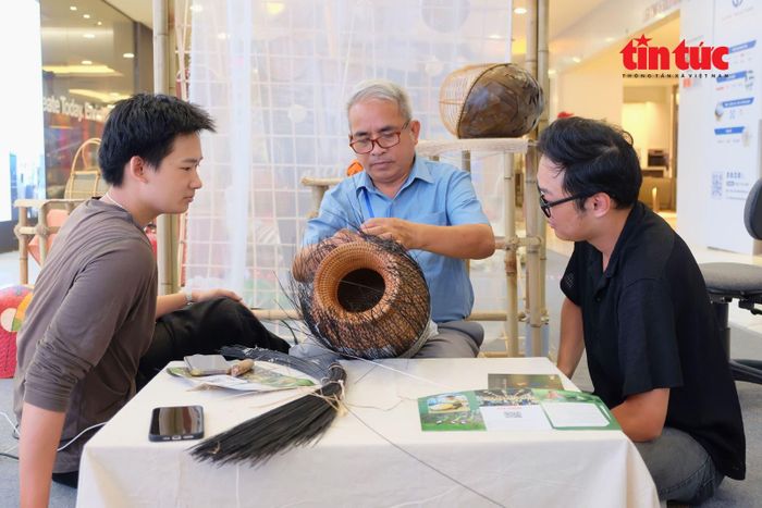 Nghệ nhân Nhân dân Nguyễn Văn Tĩnh hướng dẫn hai bạn trẻ cách làm sản phẩm mây tre đan.
