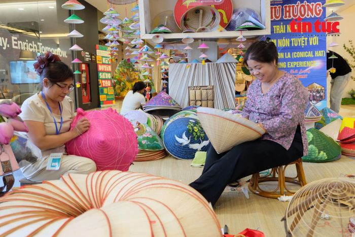 Nghệ nhân Tạ Thu Hương (bên phải) biểu diễn làm nón lá làng Chuông tại trung tâm thương mại.