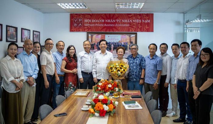 Các đại biểu tặng hoa chúc mừng và chụp ảnh lưu niệm tại lễ trao tặng Kỷ niệm chương “Vì sự nghiệp Xây dựng và Phát triển Doanh nhân Việt Nam” cho bà Nguyễn Thị Nga và ông Nguyễn Trung Chính - Ảnh Tiến Dũng. 