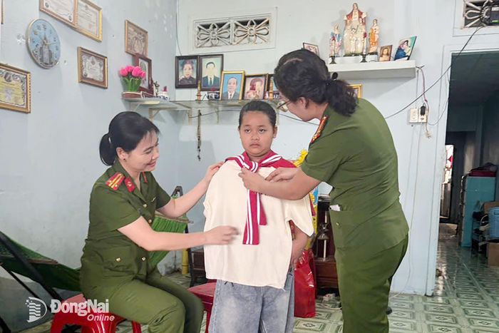 Trung tá Trần Thị Minh Huệ (trái), Trưởng Công an xã An Viễn thăm, tặng quà cho em Đỗ Ngọc Gia Hân là con nuôi công an xã An Viễn.
