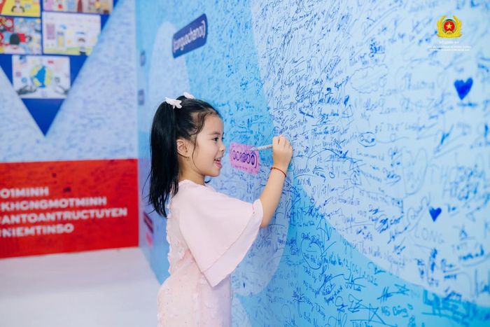 Một em nhỏ viết thông điệp lên bức tường “Không một mình”, gửi gắm mong muốn về một cuộc sống an toàn, bình yên. Ảnh: Cục An ninh mạng và phòng, chống tội phạm sử dụng công nghệ cao