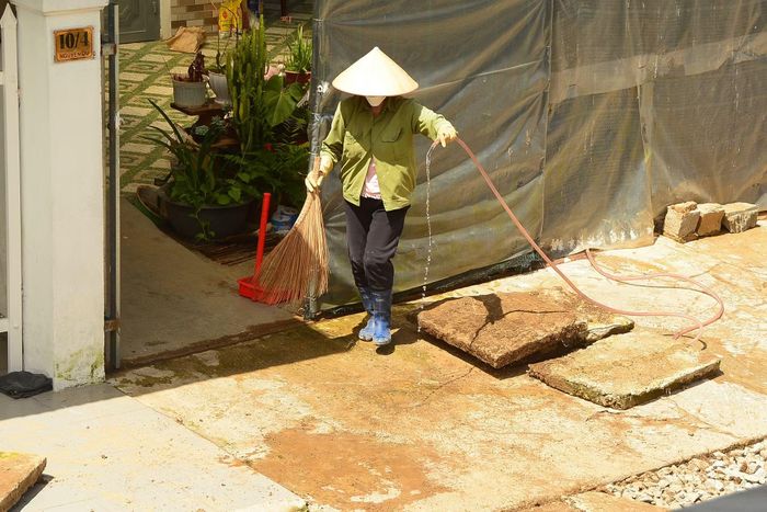 Bà Nguyễn Thị Hồng Loan dọn dẹp nhà cửa sau cơn mưa lớn chiều 14/6.