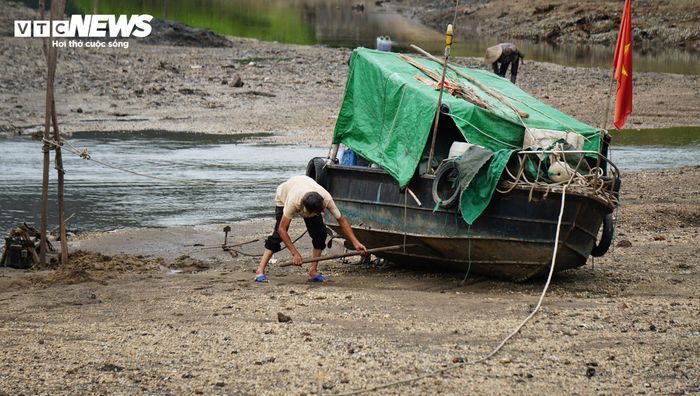 Ông Trần Quang Dũng tranh thủ cạo hà trong lúc tàu mắc cạn tại khu vực cảng Cái Xà Cong do nước rút.