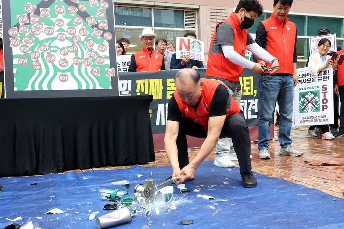 Một nhà hoạt động đập vỡ cốc, ly Starbucks trong cuộc biểu tình phản đối chiến dịch “Ngày Xe Tăng” của hãng tại Gwangju, Hàn Quốc, ngày 21/5. Ảnh: Reuters.