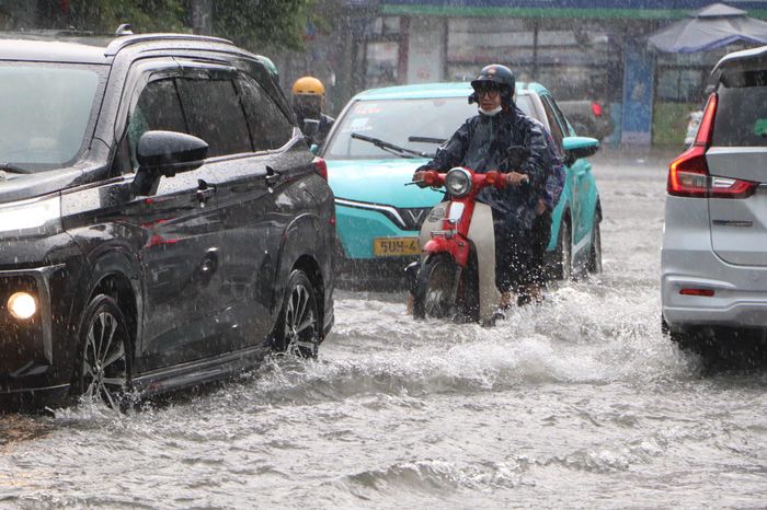  Người đi xe máy, ô tô di chuyển giữa dòng nước ngập trên đường Thảo Điền, phường An Khánh 