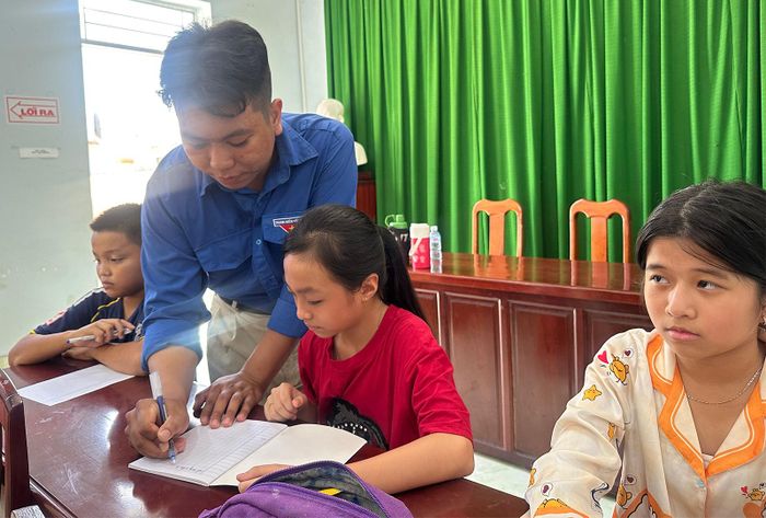 Anh Nguyễn Minh Hậu hướng dẫn học sinh học bảng cửu chương. Ảnh: TƯỜNG VI