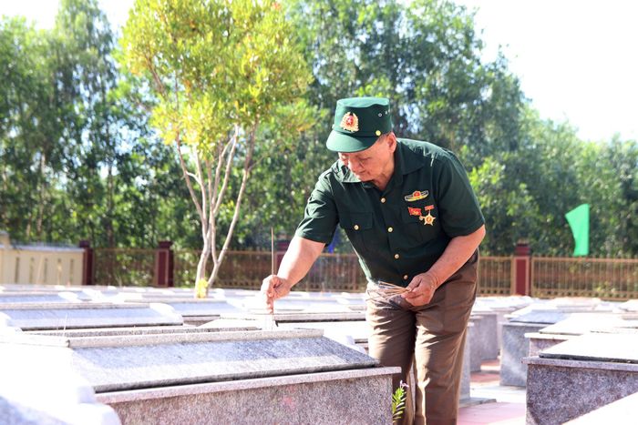 Cựu chiến binh thắp hương các phần mộ liệt sĩ tại Nghĩa trang Liệt sĩ xã Hà Nha. Ảnh: TRỌNG HUY